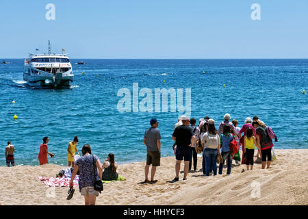 Tourists waiting for a cruise boat on the beach in center of town on May 20, 2016 in Lloret de Mar, Spain Stock Photo