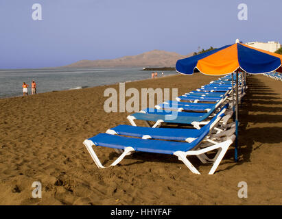 Beach sunbeds and parasol at Puerto Fl Carmen Lanzarote. Stock Photo