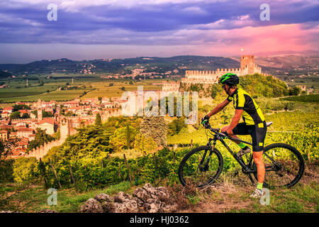 Cyclist admires from the hill the Soave castle views. Stock Photo