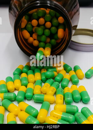 Yellow Green Pills pouring out of the brown bottle, Capsules and Medicine Bottle Stock Photo