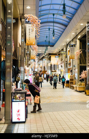 Matsuyama, Japan. The Dogo shopping arcade, known as Haikara Street, at evening time. View along modern arcade of open shops and few people walking. Stock Photo