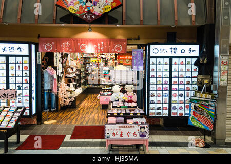 Japan, Matsuyama. Dogo shopping mall, 'Haikara Street'. Night time, interior. View into shop selling purses, dolls and other souvenirs. Stock Photo