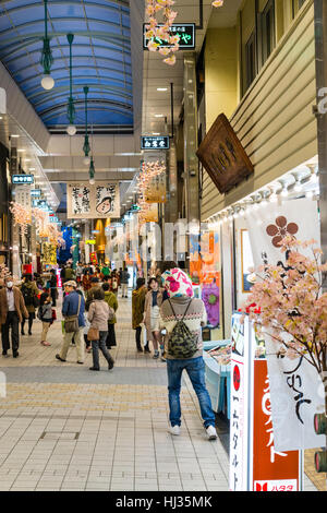 Matsuyama, Japan. The Dogo shopping arcade, known as Haikara Street, at evening time. View along modern arcade of open shops and few people walking. Stock Photo