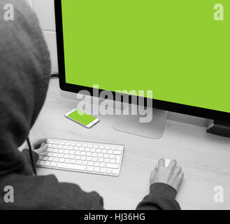 Person sat at a computer ready to work, hack, steal money, create, type, go online etc. Cell phone can also be seen on the table Stock Photo