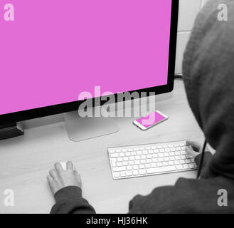 Person sat at a computer ready to work, hack, steal money, create, type, go online etc. Cell phone can also be seen on the table Stock Photo