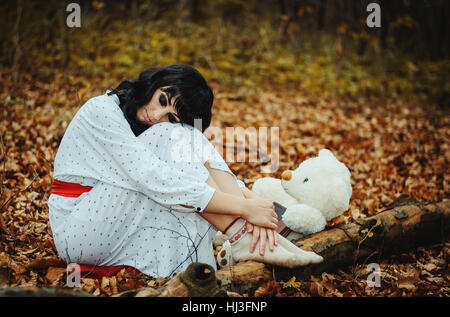 Young sad lonely brunette girl at sleepwear sitting and being taken on knees Stock Photo