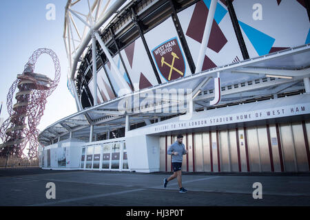 A jogger passes the London Stadium (originally known as the Olympic Stadium), now home to West Ham United football club, at the Queen Elizabeth Olympic Park in Stratford, east London. The London Legacy Development Corporation has set out an ambitious plan to regenerate the area around the site of the 2012 Olympic Games, creating a mix of housing, business space and public amenities. Stock Photo