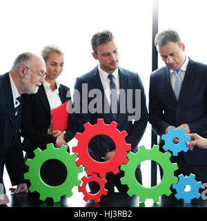 Business people assembling cogwheels, teamwork concept Stock Photo