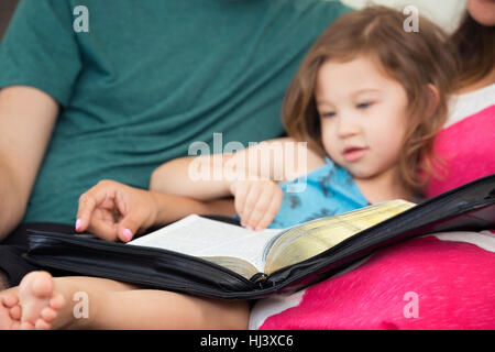 Young family studying the Word of God on the couch Stock Photo