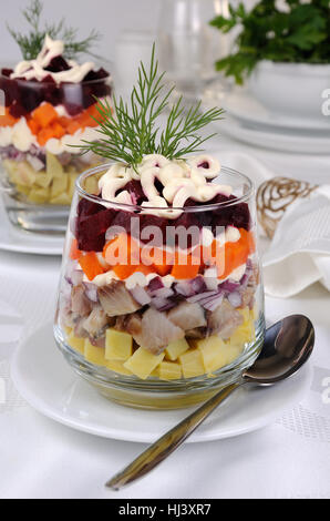 Salad of chopped herring with onions, potatoes, beets, carrots, seasoned with yogurt sauce in a glass Stock Photo