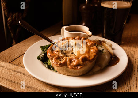 Traditional savory chicken pot pie served in pub with beer in the background Stock Photo