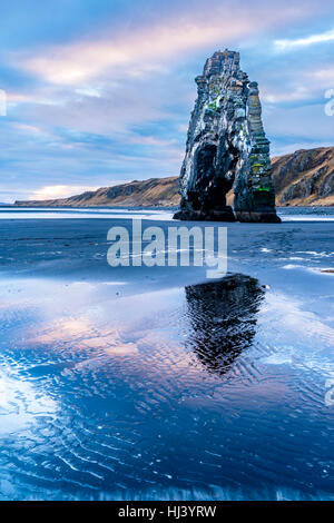 A landmark beach in Iceland called Dinosaur Rock protrudes 50 feet out of the shallow water during an early morning sunrise. Stock Photo