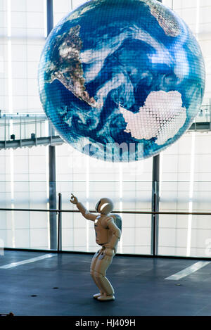 Honda's ASIMO robot points towards a giant earth at The National Museum of Emerging Science and Innovation (Miraikan) Stock Photo