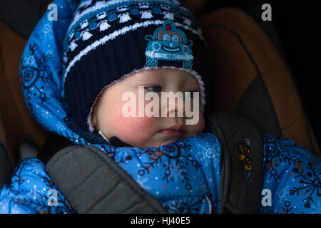 little boy in winter clothes in a child car seat