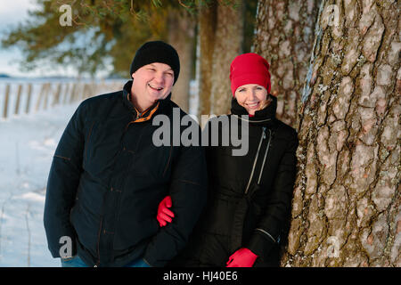 young couple near the tree in winter park Stock Photo