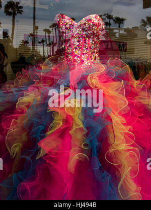 Fancy dress for quinceañera, seen through a window with palm trees reflected in the glass in McAllen Texas Stock Photo