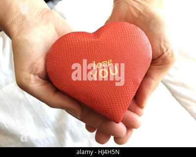 Love you. Red heart shaped gift box in woman's hands. Stock Photo