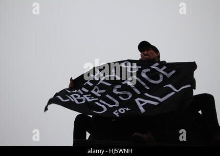 District of Columbia, USA. 21 Jan, 2017. Two men atop a pillar hold a black flag with the words "WITH LIBERTY & JUSTICE FOR ALL". Stock Photo