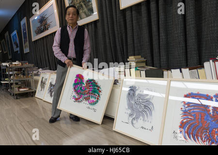 (170126) -- BEIJING, Jan. 26, 2017 (Xinhua) -- Chinese artist Han Meilin, 80, shows his paintings of roosters and hens at his studio in eastern district of Tongzhou in Beijing, capital of China, Jan. 24, 2017. Han, designer of the 2008 Beijing Olympic Games mascot 'Fuwa,' has just finished the design of Chinese zodiac stamps for the upcoming Year of the Rooster. The set of Chinese Lunar New Year rooster stamps, issued earlier this month, contain two items showing a rooster striding proudly and a hen looking after her two chicks. Han applied rich color and elements of traditional Chinese painti Stock Photo