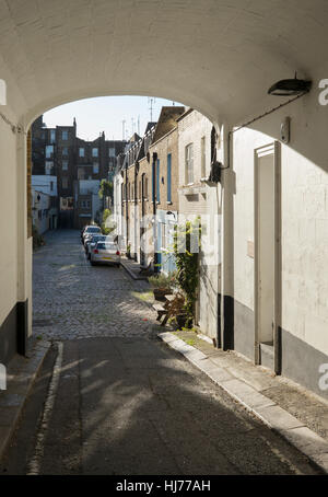 Morning sunlight shining on mews and through entrance arch, London, UK Stock Photo