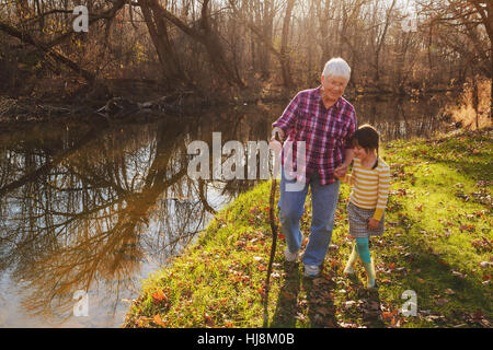 Grandmother walking by river with her granddaughter Stock Photo