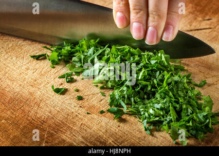 Premium Photo  Chef chopping parsley with knife on a wooden board close up