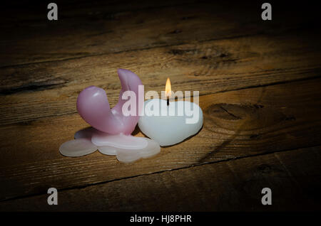 Burning candle in the form of heart on a dark background for valentine's day. Stock Photo