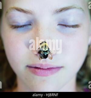 Girl with a bee on her nose Stock Photo