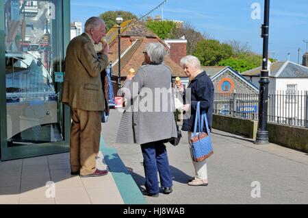 Three elderly people enjoying an ice cream on Broadstairs seafront Kent UK Stock Photo