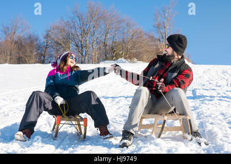 Young couple having fun on the sleds Stock Photo