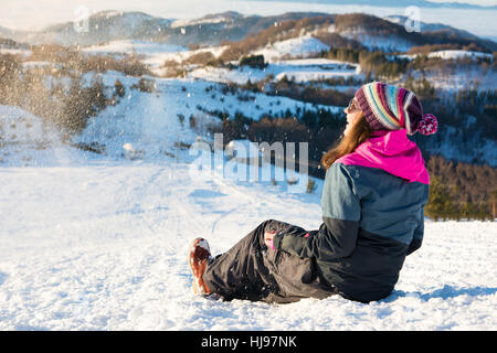 Happy girl sitting in the snow on the mountain top Stock Photo