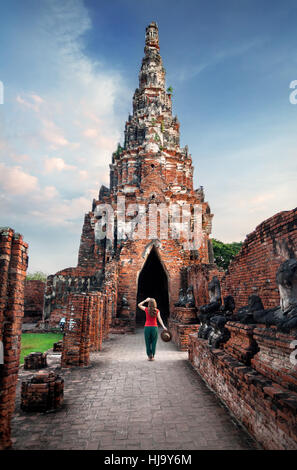 Woman tourist with hat looking at ancient ruined wat Chaiwatthanaram in Ayutthaya, Thailand Stock Photo