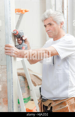 Mason drilling into a wall Stock Photo