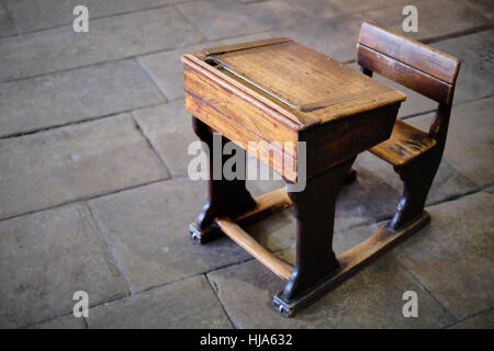 Antique, vintage, wooden school desk and chair on a Yorkshire stone flagged floor Stock Photo