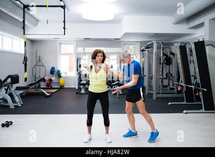 Senior couple in gym working out with weights Stock Photo
