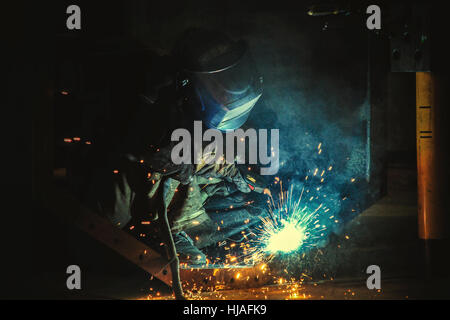 Welder welds metal parts in a protective suit Stock Photo