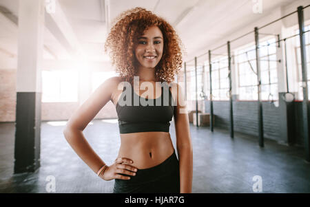 Portrait of beautiful young african woman in gym. fitness model posing in the gym and smiling. Stock Photo