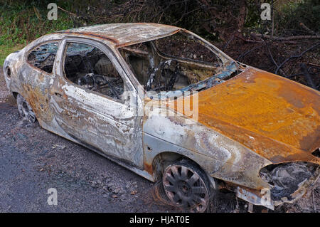 A burnt out car on the road just outside St Agnes, Cornwall. Stock Photo