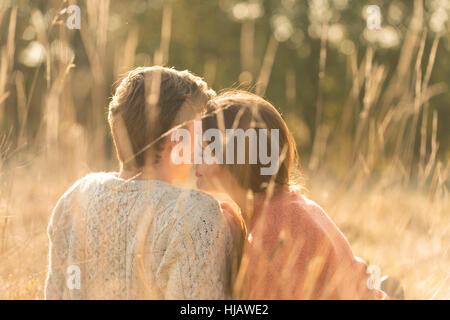 Young couple sitting in rural setting, kissing Stock Photo