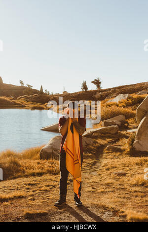 Young male hiker by lake drying face with towel, Mineral King, Sequoia National Park, California, USA Stock Photo