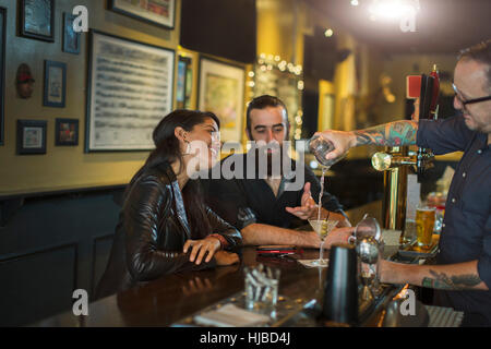 Bartender pouring cocktail for young couple in public house Stock Photo
