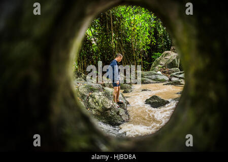 Young man watching flowing stream, Secret Buddha Garden, Koh Samui, Thailand Stock Photo