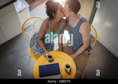 High angle view of romantic young couple kissing at kitchen table Stock Photo