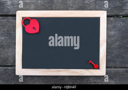 Table for Valentine's Day. Heart shaped red padlock with key on blackboard Stock Photo