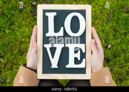 gilr hands holding a blackboard with the words ' Love' Stock Photo