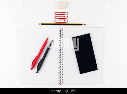 Office Workspace on white background with smartphone. Notebook Blank with pencil, pen and clips. Copy space for text or Image Stock Photo