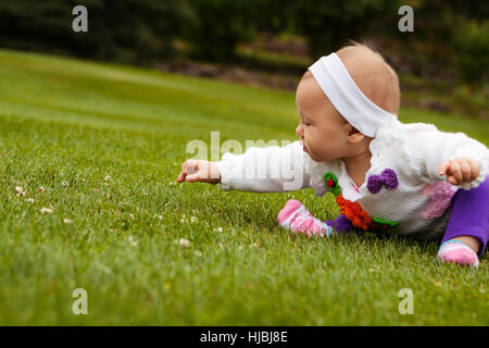 Beautiful baby girl playing on grass field Stock Photo