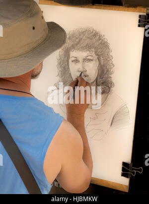 Street artist at work, drawing a portrait of a pretty woman with curly hair, on Charles Bridge, Prague 1, Czech Republic. Stock Photo