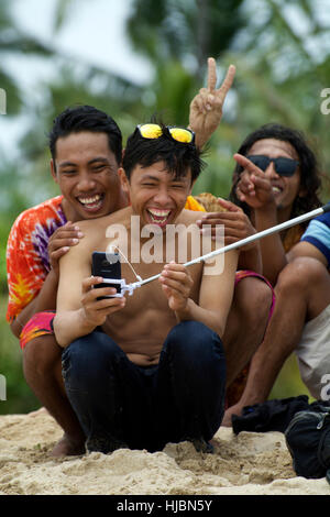 Friendly group of young Balinese men poise for selfie photo with selfie stick showing young cool laughs, smiles and warmth Stock Photo