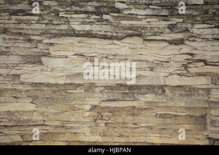 A background cliff face of weathered sedimentary limestone with cracks in it. Stock Photo